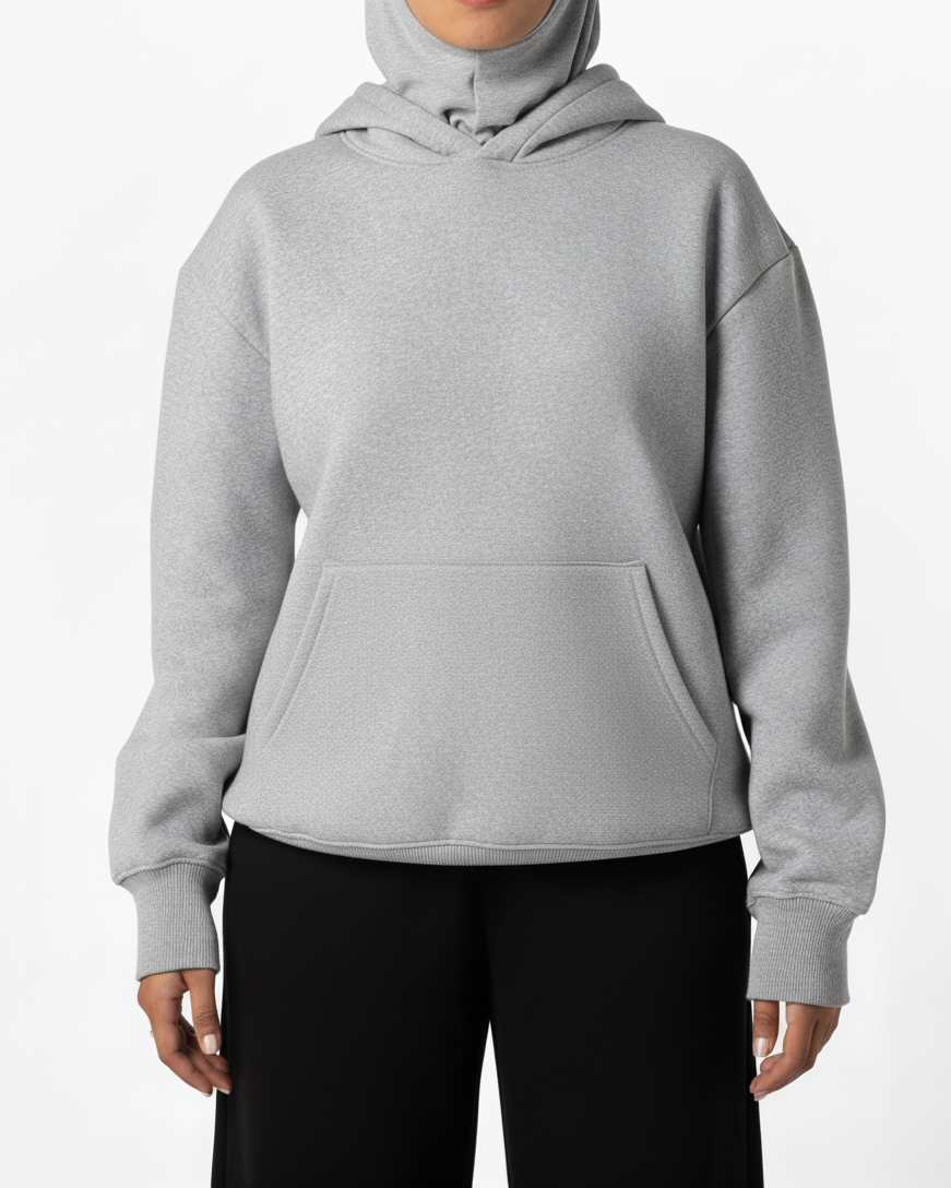 Person wearing a gray hoodie and black pants on a white background