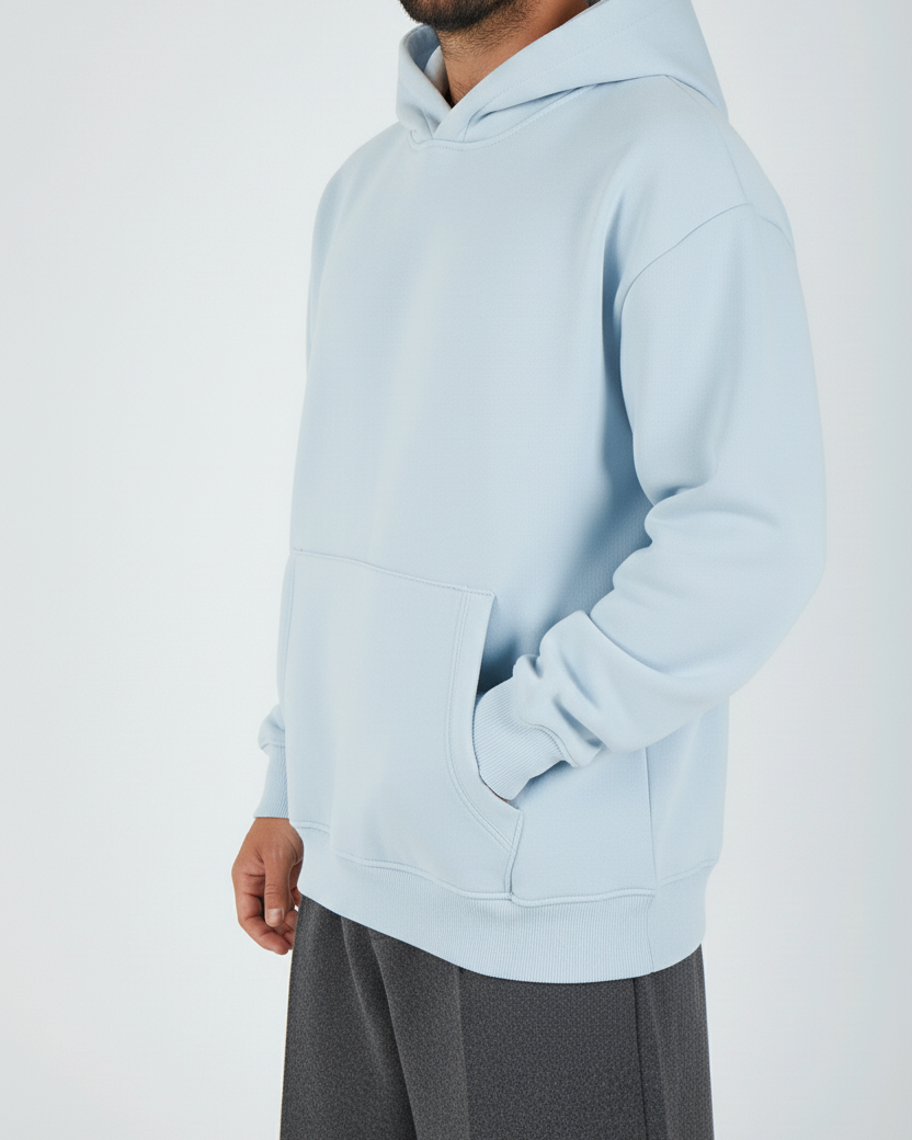 Man wearing a light blue hoodie and gray pants on a white background