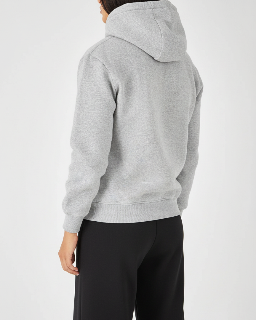 Person wearing a gray hoodie and black pants on a white background