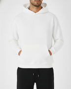 Person wearing a white hoodie and black pants on a white background