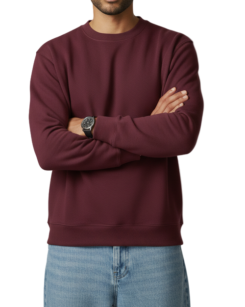 Man wearing a maroon sweatshirt and light blue jeans against a plain background