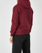 Person wearing a red hoodie and black pants on a white background