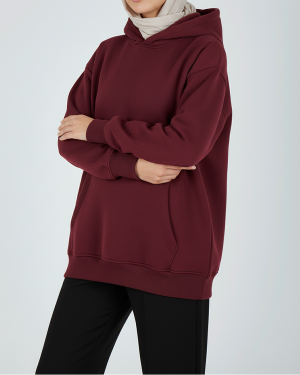 Woman wearing a maroon hoodie and black pants on a white background
