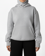 Person wearing a gray hoodie and black pants on a white background