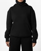 Person wearing a black hoodie and pants on a white background