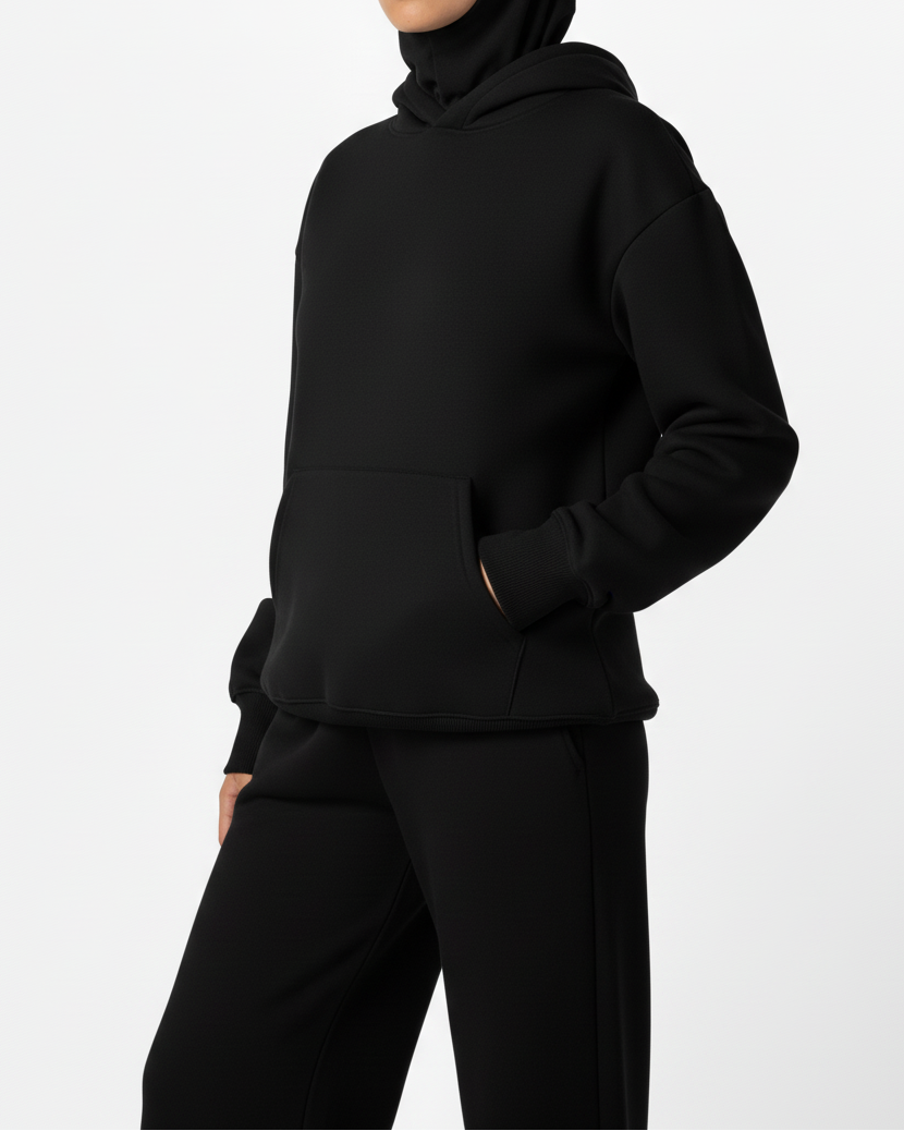 Person wearing a black hoodie and pants on a white background