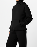 Person wearing a black hoodie and pants on a white background