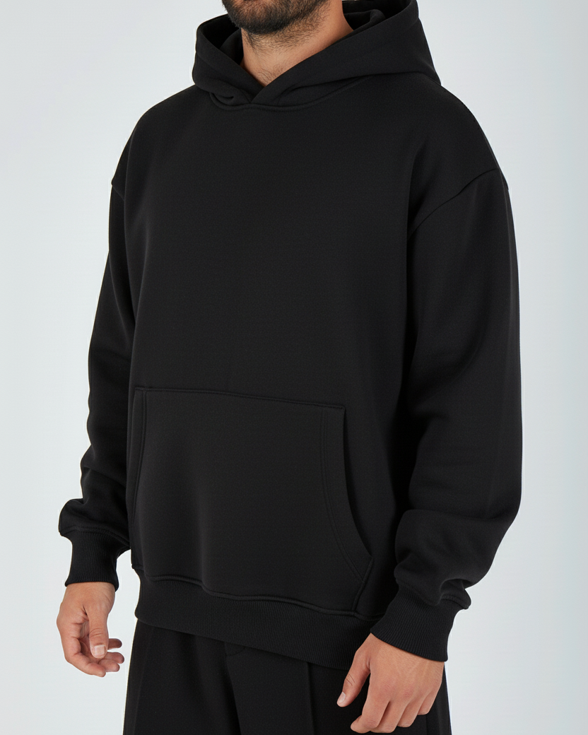 Person wearing a black hoodie and pants on a white background