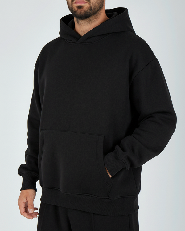 Person wearing a black hoodie and pants on a white background