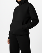 Person wearing a black hoodie and pants on a white background