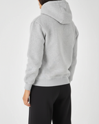 Person wearing a gray hoodie and black pants on a white background